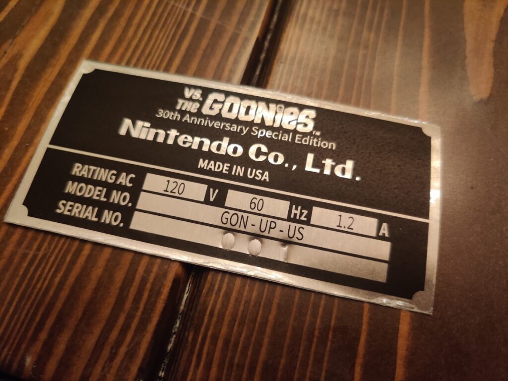An aluminum Goonies arcade serial card